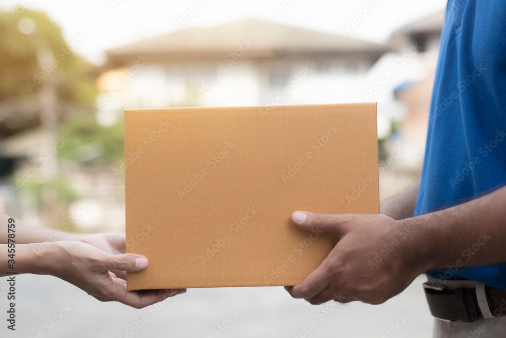 Wall mural Woman hand accepting a delivery boxes of paper containers from deliveryman.