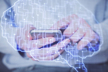 Double exposure of man's hand holding and using a digital device and brain hologram drawing. Data concept.