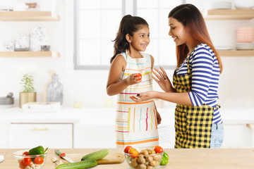 Mother and daughter cooking together in kitchen
