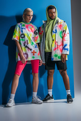 Obraz premium stylish multicultural couple posing in colorful futuristic look on grey and blue
