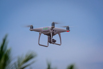 Drone is flying with digital camera to take photo and video on ground at sunset time.