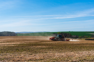 Fototapeta na wymiar Farmer in tractor sowing wheat field at spring , czech jeseniky 04.16.2020