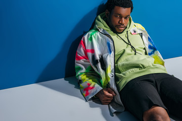 handsome african american man posing in colorful futuristic look on grey and blue