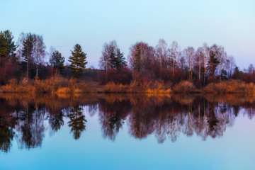 Panoramic soft focus photo of reflection in a river of trees at sunset. Trees are reflected in the river like sound waves. The music of the forest. Landscape collection 