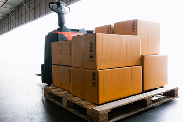 electric forklift pallet jack unloading shipment goods, stack package boxes on pallet, warehouse delivery service shipment and transport.