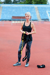 Fototapeta na wymiar woman with short cut preparing for training with TRX outdoor , .checks fastener system, carabiner