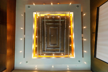 Fototapeta premium look up on suspended ceiling with halogen spots lamps and drywall construction with fire alarm sensor in empty room in apartment or house. Stretch ceiling white and complex shape.