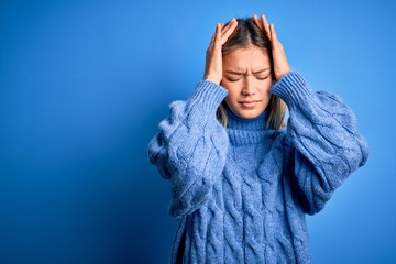 Young beautiful blonde woman wearing winter wool sweater over blue isolated background suffering...