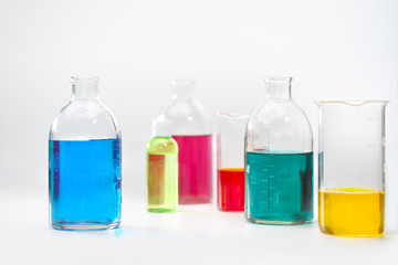 Glass bottles and flasks of different sizes with liquids of different colors on the background. Chemical lab.