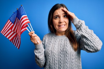 Young patriotic woman holding usa flag on independence day 4th of july over blue background...