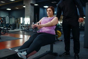 Fototapeta na wymiar Overweight woman with trainer in sport club