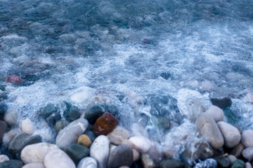 Sea waves breaking on pebbles. Pebbles through sea water.