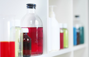 Many different bottles and test tubes with liquids of different colors stand on the shelf. Pharmacy.