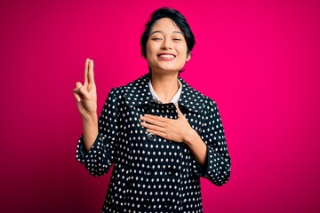 Young beautiful asian girl wearing casual jacket standing over isolated pink background smiling swearing with hand on chest and fingers up, making a loyalty promise oath