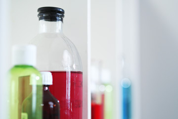 Many different bottles and test tubes with liquids of different colors stand on the shelf. Pharmacy.