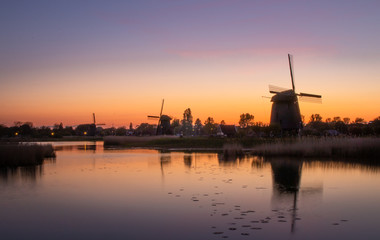 Fototapeta na wymiar Holenderskie wiatraki nad kanałem wodnym, zachód słońca w Holandii Północnej