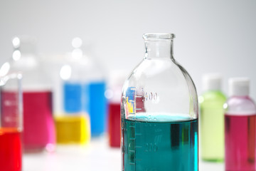 Glass bottles and flasks of different sizes with liquids of different colors on the background. Chemical lab.