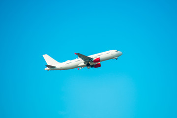 Big white flying plane on blue sky and clouds background