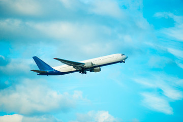 Naklejka na ściany i meble View of big white flying plane on blue sky and clouds background