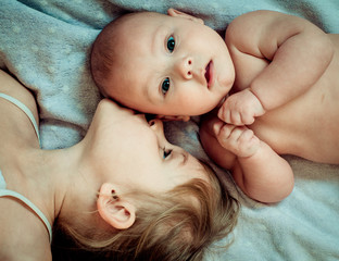 portrait close-up sister with newborn brother lying on the bed