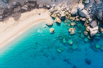 Top-down aerial view of a clean white sandy beach on the shores of a beautiful turquoise sea....