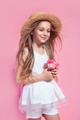 Little pretty girl with flower dressed in white dress and straw hat