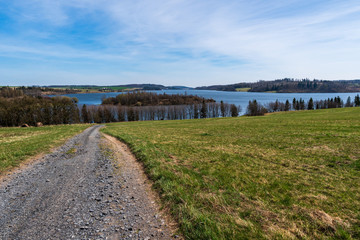 Fototapeta na wymiar pasture with beautiful lake and blue-white sky on a sunny day