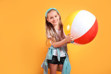 Funny happy child in summer holding beachball on yellow background