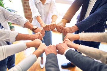 Group of business workers standing bumping fists at the office