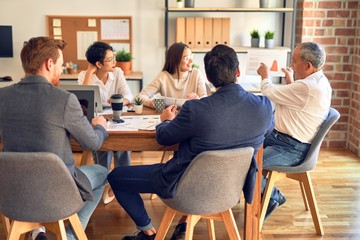 Group of business workers working together. Sitting on desk using laptop reading documents at the office