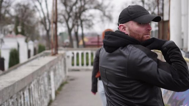 A man thief steals a woman's bag on the street, a view from the back. Slow motion.