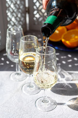 Pouring of cold fino sherry fortified wine in glass in sunlights, andalusian style interior on background