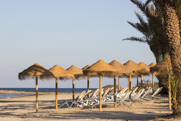 Sunbeds and sunshades in a beach with a blue sky
