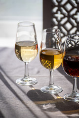 Glasses with cold dry fino and sweet cream sherry fortified wine in sunlights, andalusian style interior on background