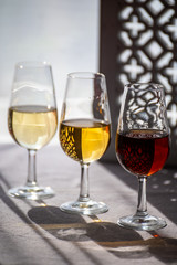 Glasses with cold dry fino and sweet cream sherry fortified wine in sunlights, andalusian style interior on background