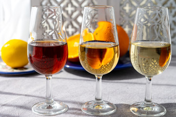 Glasses with cold dry fino and sweet cream sherry fortified wine and orange in sunlights, andalusian style interior on background