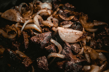 Fried with onions meat from pork in a frying pan.