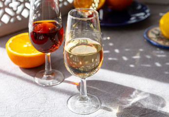 Glasses with cold dry fino and sweet cream sherry fortified wine and orange in sunlights, andalusian style interior on background