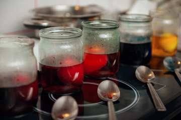 Glass jars with colorful Easter eggs and spoons, process of coloring Easter eggs