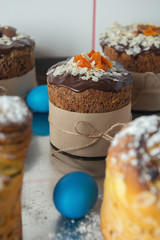 Brown Easter cakes decorated with chocolate, almond flakes and dried apricots on kitchen table among easter eggs