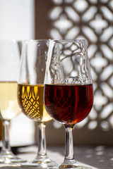 Glasses with cold dry fino and sweet cream sherry fortified wine in sunlights, andalusian style interior on background