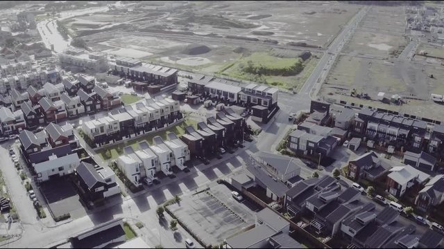 Aerial Drone Flying Down Over Housing In Hobsonville Point In Auckland, New Zealand With Empty Housing Lots In The Background.