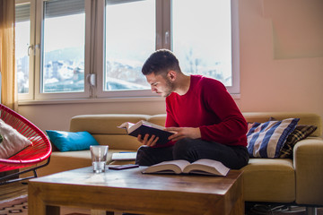 Man reading book of knowledge on sofa