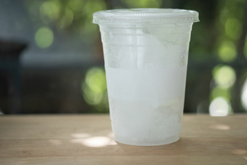 Plastic glass with ice on wood table