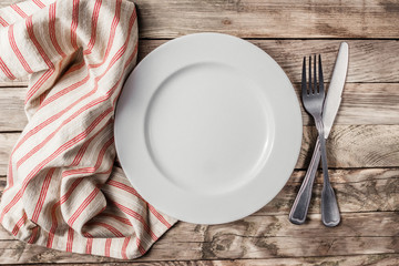 Vintage Table setting with napkin, fork, knife and plate on old rustic wooden table