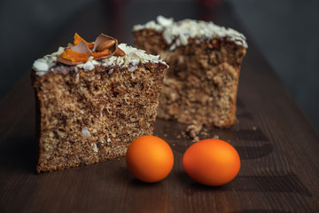 Cut Easter cake decorated with chocolate, almond flakes and dried apricots among colored Easter eggs