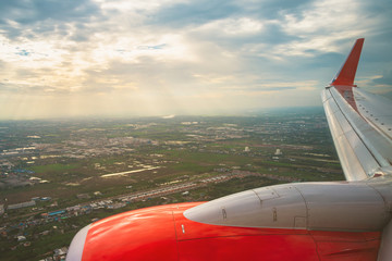 Beautiful scenic city view of sunset through the aircraft window..Airplane interior with window view of blue sky and wing..Looking through window aircraft during flight in wing with a nice blue sky.