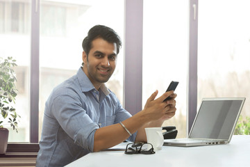 Portrait of smiling executive at desk using mobile phone
