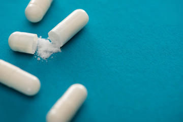 close up view of probiotic capsules with white powder on blue background