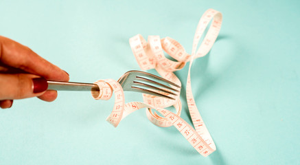 fork and knife with a centimeter on a blue background, diet, healthy lifestyle.